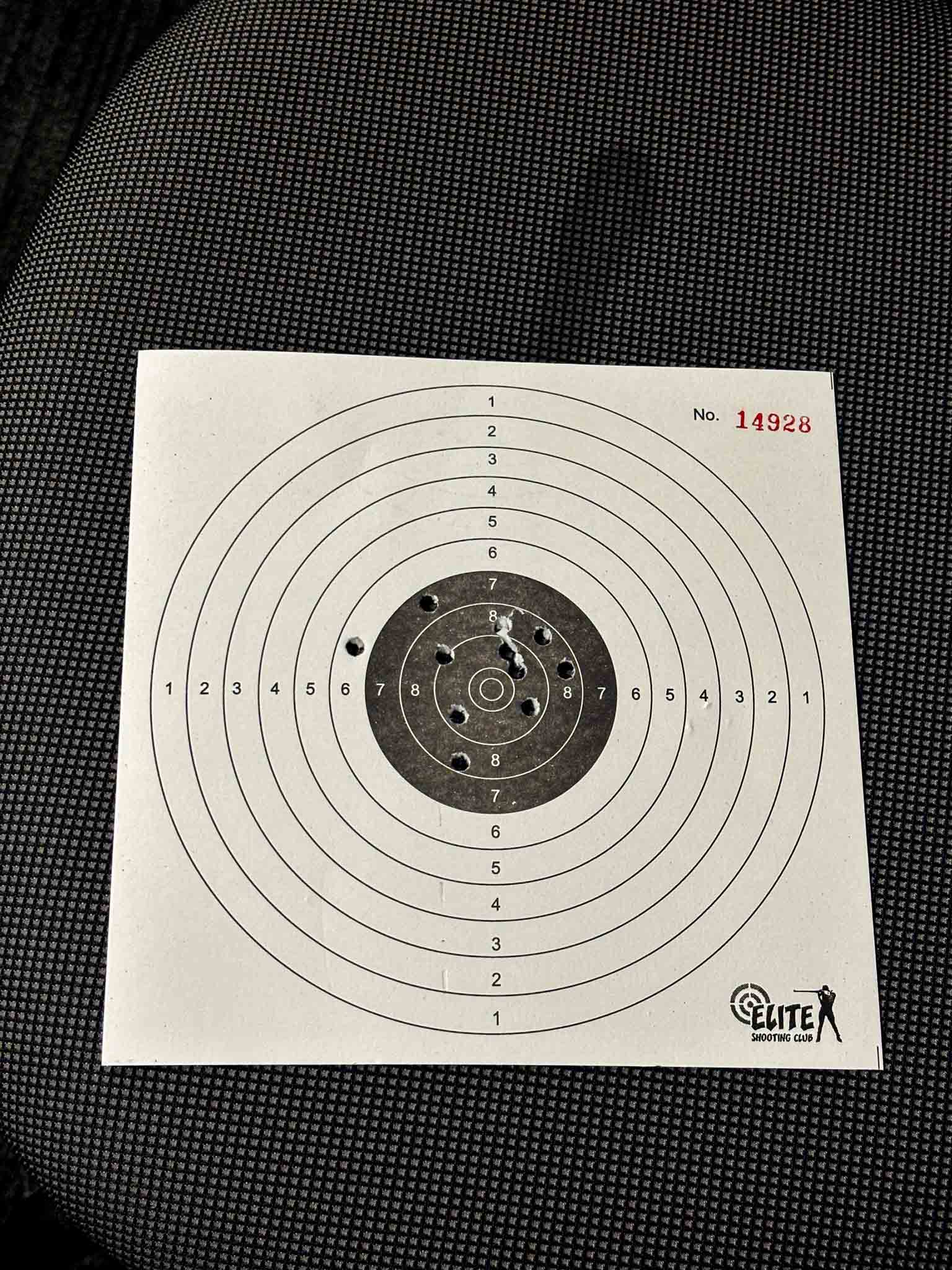 A focused male participant aligning a rifle while aiming at shooting targets indoors.